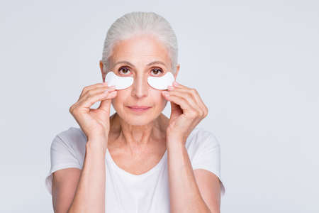 Close up photo of charming grandmother applying gel holding cotton pad wearing stylish trendy...