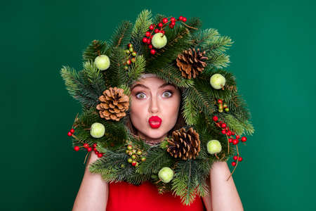 Close-up portrait of her she nice attractive pretty flirty coquettish funky girl holding in hands festive wreath having fun sending air kiss good mood isolated over green color backgroundの写真素材