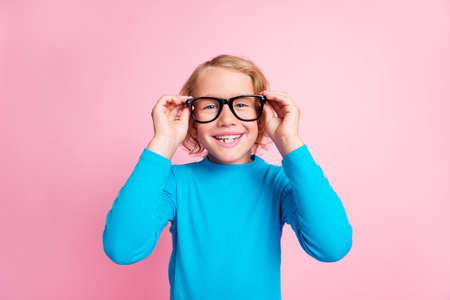Photo of small schoolkid hands take off hold glasses wear specs blue turtleneck isolated pastel pink color backgroundの写真素材