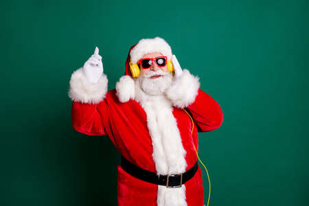 Portrait of his he nice attractive handsome cheerful Santa father listening different pop music soul jazz bass single having fun enjoying dancing isolated over green color backgroundの写真素材