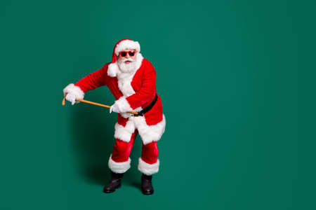Full length body size view of his he nice attractive cheerful cheery childish funky Santa father dancing with cane having fun celebratory festive day fooling isolated over green color backgroundの写真素材