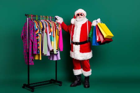 Full length body size view of his he nice fat fat cheerful Santa father buyer visit outlet center bargain carrying buyings things choose choice season garment isolated over green color backgroundの写真素材