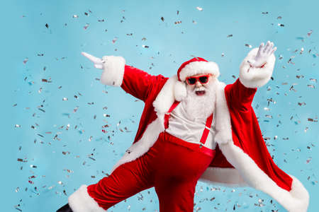 Boss of life. Photo of pensioner old man grey beard careless raise hand dance open mouth vip event confetti wear santa x-mas costume suspender sunglass cap isolated blue color backgroundの写真素材