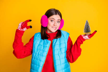 Photo of frustrated girl feel guilty she choose small christmas evergreen tree bite lips teeth wear stylish trendy sweater isolated over bright shine color backgroundの写真素材