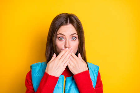 Omg unbelievable. Close up portrait of shocked girl tell say her friends secret feel guilty close cover hands lips wear season sweater isolated over bright shine color backgroundの写真素材