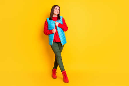 Full body size photo of cute lovely young lady beaming smiling look empty space posing watch star fall wear green pants blue vest red sweater boots isolated bright yellow color backgroundの写真素材