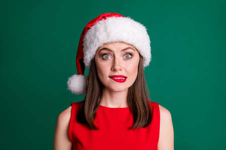 Closeup photo of attractive charming terrified lady bite lips late with party decorations oh no santa will scold me wear x-mas cap red dress isolated green pastel color backgroundの写真素材
