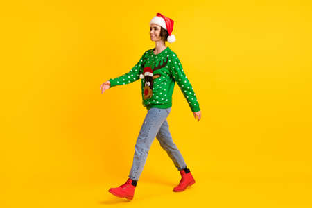 Full length profile side photo positive girl in santa claus headwear go walk copyspace x-mas christmas theme party wear deer decor sweater jeans boots isolated bright shine color backgroundの写真素材