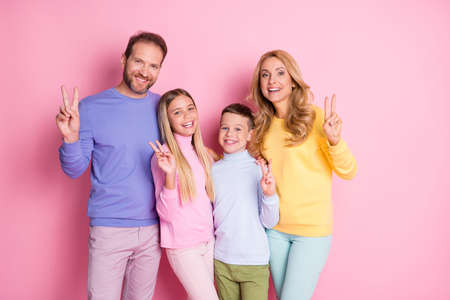 Photo of positive family daddy mommy and small kids girl boy make v-sign isolated over pastel color backgroundの写真素材