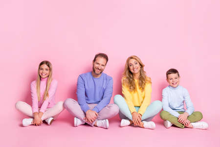 Full size photo of charming family daddy mommy small boy girl sit floor legs crossed isolated on pastel color backgroundの写真素材