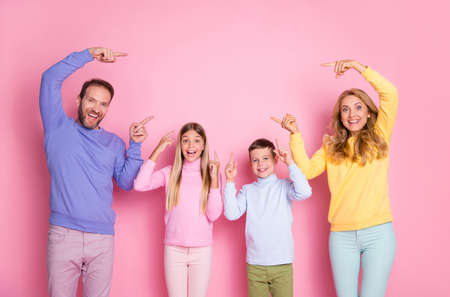 Photo of surprised mommy daddy small kids point index finger empty space isolated over pastel color...
