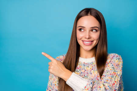 Closeup photo of attractive cheerful lady long straight hairdo direct fingers side look empty space advising vaccination banner rules wear casual sweater isolated blue color backgroundの写真素材