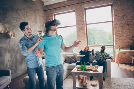 Portrait of four nice attractive glad cheerful cheery guys gathering having fun using vr device...