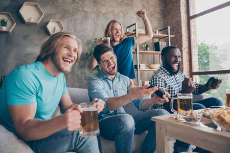 Portrait of four nice attractive cheerful cheery ecstatic guys playing video game sport battle contest having fun spending weekend at industrial loft style interior house apartment flat indoorsの写真素材