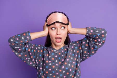 Photo of shocked crazy girl close cover hands cant sleep neighbors loud music noise wear dotted pajama eye mask isolated over purple color backgroundの写真素材