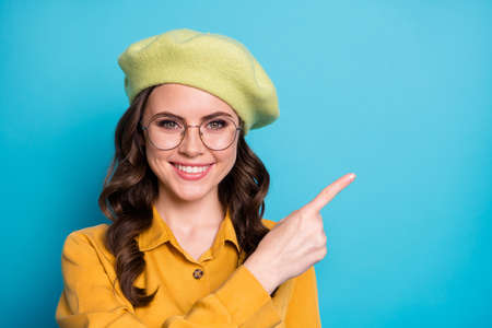 Close up photo of positive cheerful girl promoter point index finger copyspace present sales ads promo wear good look clothes isolated over blue color backgroundの写真素材