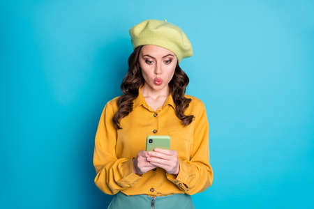 Portrait of astonished girl use cellphone impressed social network coronavirus information wear good look outfit isolated over blue color backgroundの写真素材