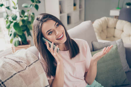 Photo portrait of woman talking on the phone sitting on couch indoors