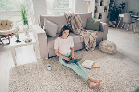 Photo portrait of woman sitting on floor rug with stretched legs laptop on top indoors