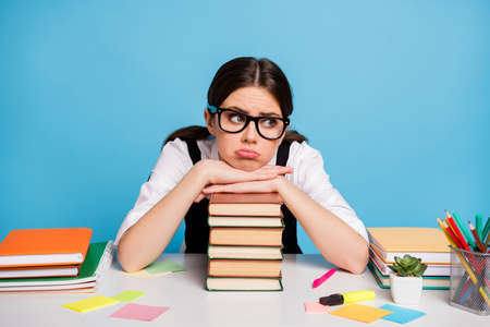 Photo of frustrated girl college student sit table put hands head pile stack textbook disappointed...