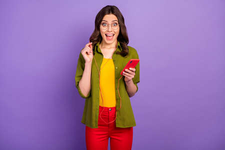 Portrait of astonished positive girl use smartphone listen incredible radio melody headset impressed...