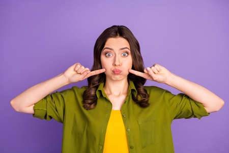 Portrait of her she nice attractive lovely cute funky wavy-haired girl pointing at cheeks holding air fooling isolated over bright vivid shine vibrant lilac violet purple color backgroundの写真素材