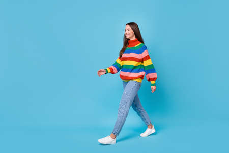 Full length body size profile side view of her she nice attractive pretty cheerful cheery girl walking wearing cosy garment clothes springtime isolated bright vivid shine vibrant blue color backgroundの写真素材