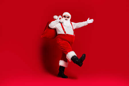 Full length body size view of his he attractive cheerful cheery Santa father carrying big large sack delivery sale discount going isolated bright vivid shine vibrant red color backgroundの写真素材