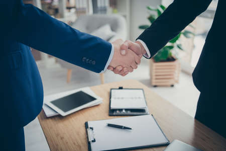 Cropped close-up view of two male hands shaking over table desk signed corporate contact assignment car life insurance service in light white interior work place station indoorsの写真素材
