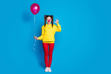Full length body size view of nice attractive creepy evil mad aggressive girl circus clown holding...