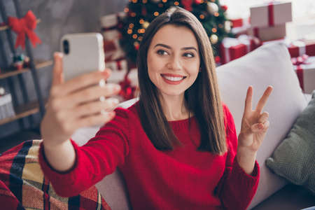Photo of positive girl take selfie on smartphone make v-sign in house indoors with x-mas christmas...