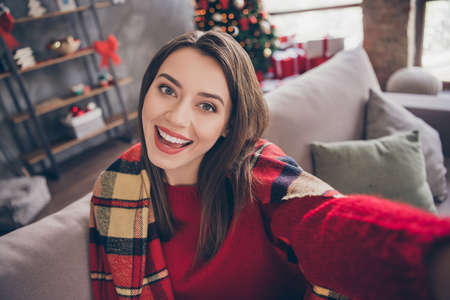 Photo of pretty cute girl sit sofa take selfie open mouth wear blanket red pullover in decorated x-mas living room indoorsの写真素材