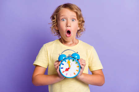 Photo of astonished small boy feel frustrated hold clock missed late time concept isolated over...