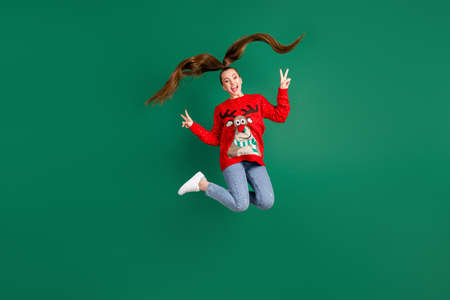 Full length photo of attractive cute lady jump high x-mas party good mood greet friends show v-sign...