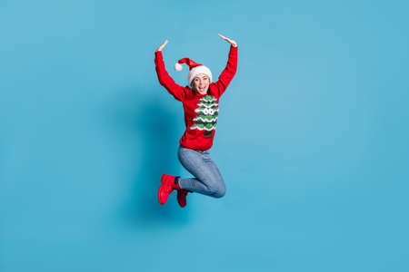Portrait photo of jumping high happy laughing smiling girl keeping hands over head wearing funny red...