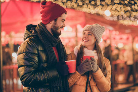 Photo of positive couple hold tradition eggnog beverage mug under x-mas christmas outside evening...