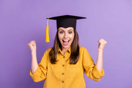 Close-up portrait of her she attractive cheerful lucky girl wearing graduate cap celebrating win winner rejoicing isolated on bright vivid shine vibrant lilac violet color backgroundの写真素材