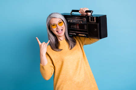 Photo of pretty hipster rocker aged woman excited look open mouth hold boom box walk street listen...