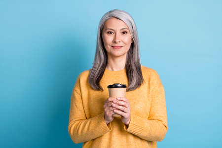 Photo of pretty calm aged woman white grey hairdo hold cup coffee drink have comfort free morning time cafe family wear yellow jumper denim isolated blue pastel color backgroundの写真素材