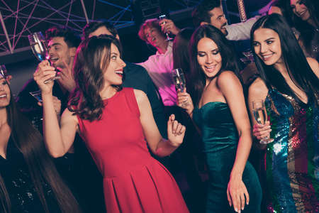 Photo portrait of cool millennials holding champagne glasses dancing at nightclub