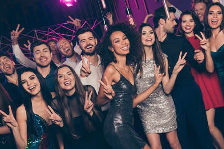 Photo portrait of friends showing many v-signs dancing at new year partyの写真素材