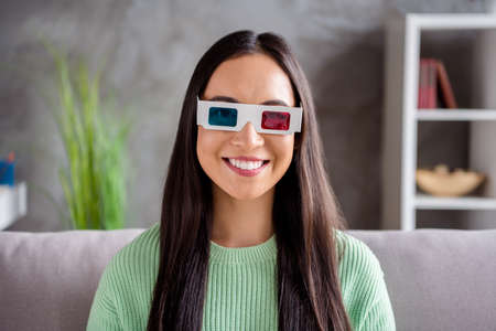 Close up photo of nice chinese girl watch 3d film glasses enjoy modern effect sit divan in house...