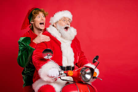 Profile photo of elf santa ride moped open mouth look empty space wear x-mas costume coat cap isolated red color backgroundの写真素材