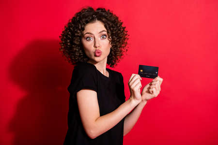 Photo of adorable funny wavy lady dressed casual black outfit holding credit card lips pouted...
