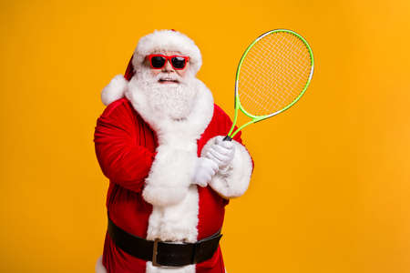 Portrait of his he nice attractive confident cheerful cheery experienced Santa enjoying playing badminton team cup league contest isolated bright vivid shine vibrant yellow color backgroundの写真素材