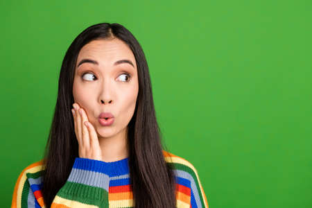 Close-up portrait of attractive amazed girl looking aside copy empty blank space pout lips isolated over vivid green color backgroundの写真素材