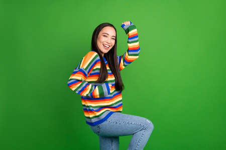 Profile side view portrait of attractive cheerful girl dancing having fun isolated over bright green color backgroundの写真素材