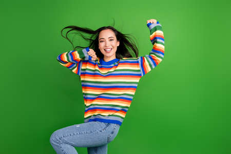Portrait of charming cheerful girl dancing having fun air blowing isolated over bright green color backgroundの写真素材
