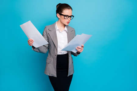 Portrait of attractive focused lady specialist reading legal documentation isolated on bright blue...