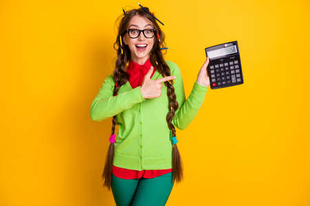 Photo of amazed girl messy hairdo point finger calculator wear shirt trousers isolated yellow color backgroundの写真素材